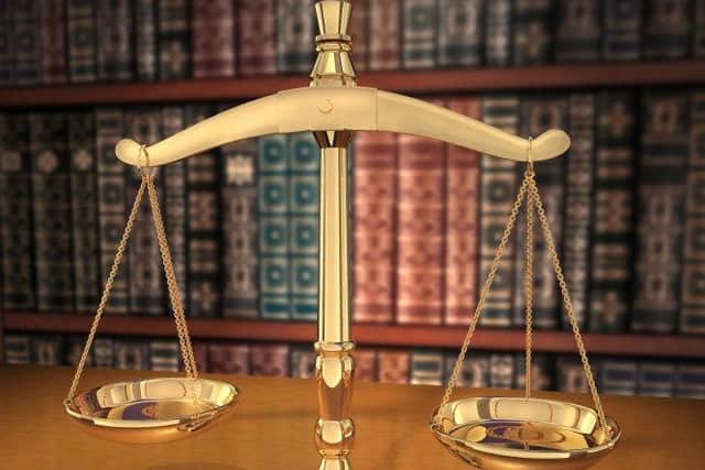 Brass Scales of Justice on a desk showing Depth-of-field books behind in the background
